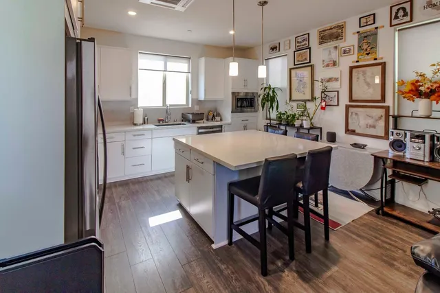 a kitchen with stainless steel appliances a dining table chairs stove refrigerator and cabinets