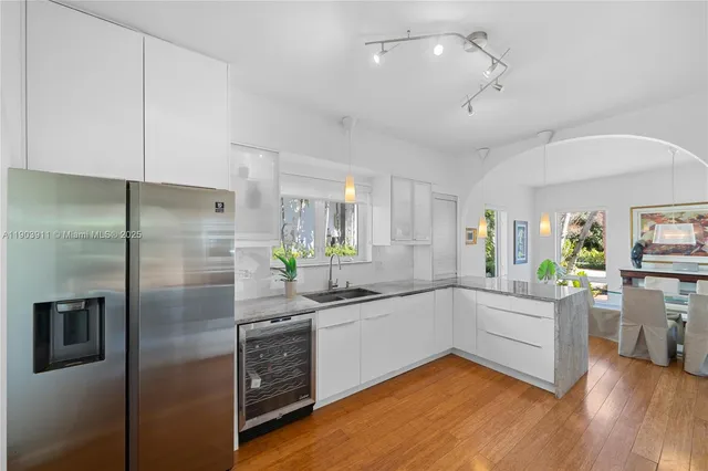 a kitchen with stainless steel appliances a refrigerator a sink a stove cabinets and wooden floor