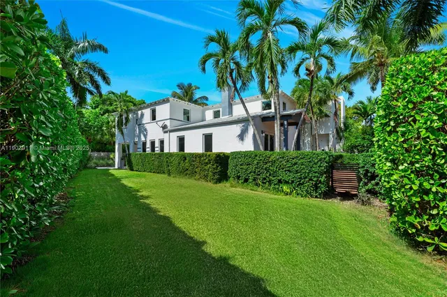 a view of a house with a big yard plants and large trees