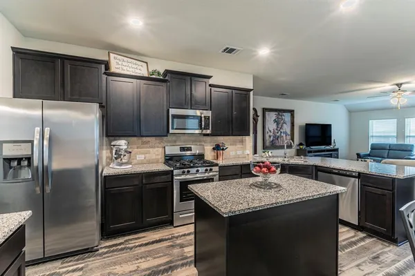 a kitchen with stainless steel appliances granite countertop a stove refrigerator sink and microwave