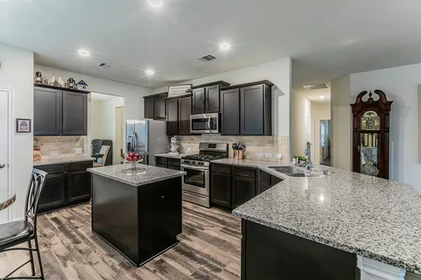 a kitchen with kitchen island granite countertop a sink stove and refrigerator