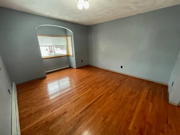 an empty room with wooden floor cabinet and windows