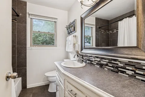 a bathroom with a granite countertop sink mirror vanity and toilet