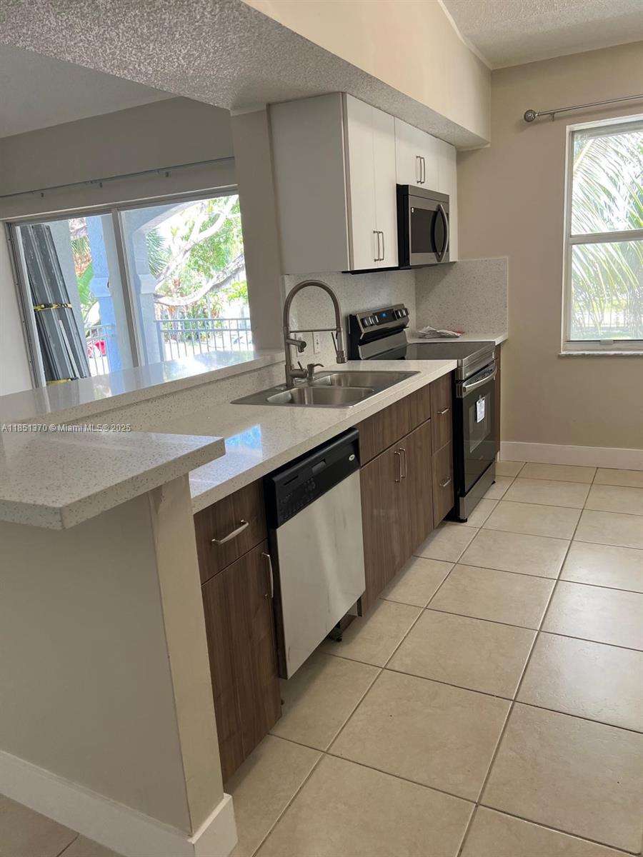 9645 Northwest 1st Court, Unit 1209 Pembroke Pines, FL 33024 - Photo 14 of 70 a kitchen with a sink stove and cabinets