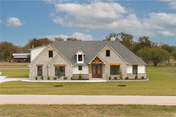 a front view of a house with a garden and trees