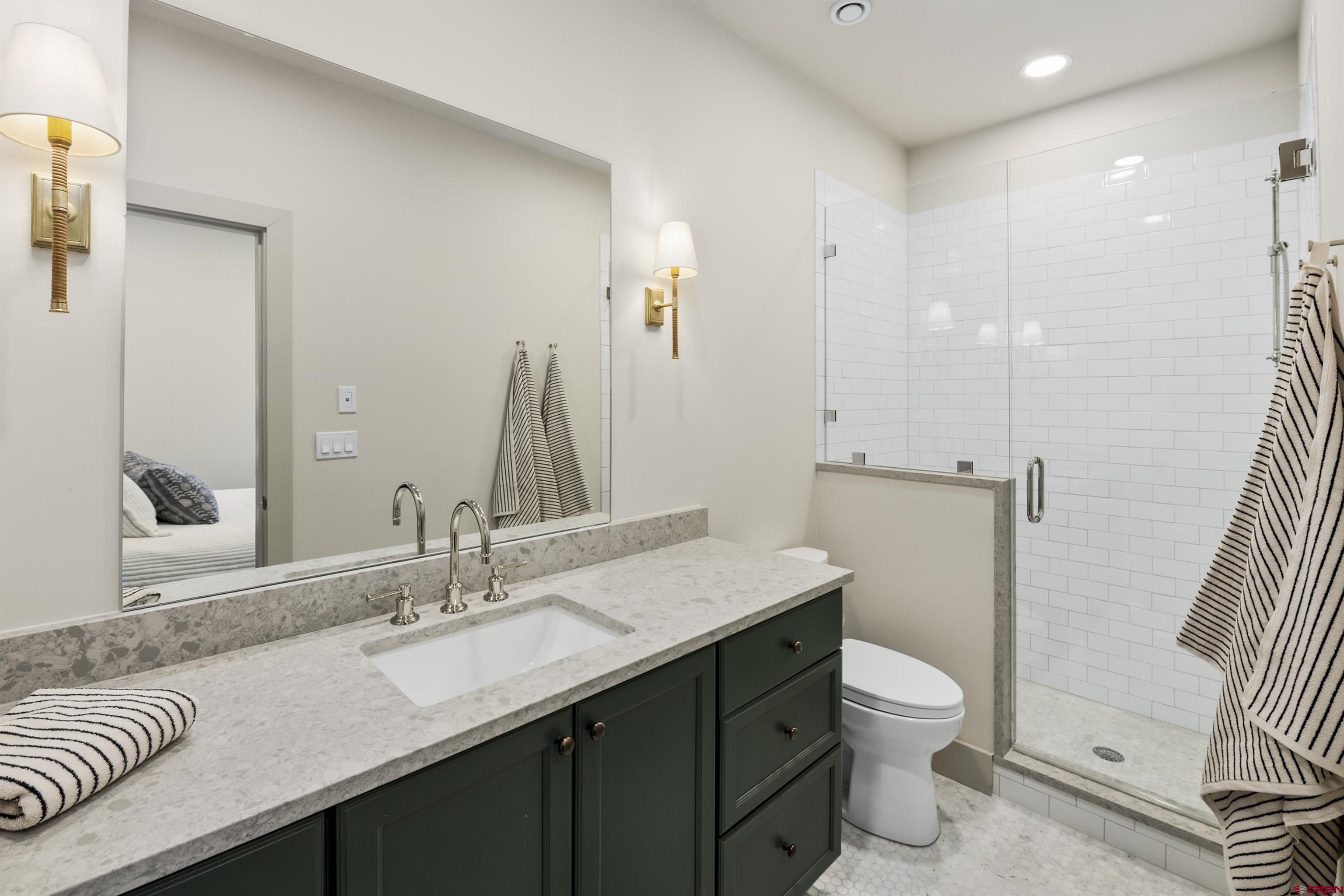 180 Elk Valley Road, Unit 118 Crested Butte, CO 81224 - Photo 28 of 39 a bathroom with a granite countertop sink a toilet and a large mirror
