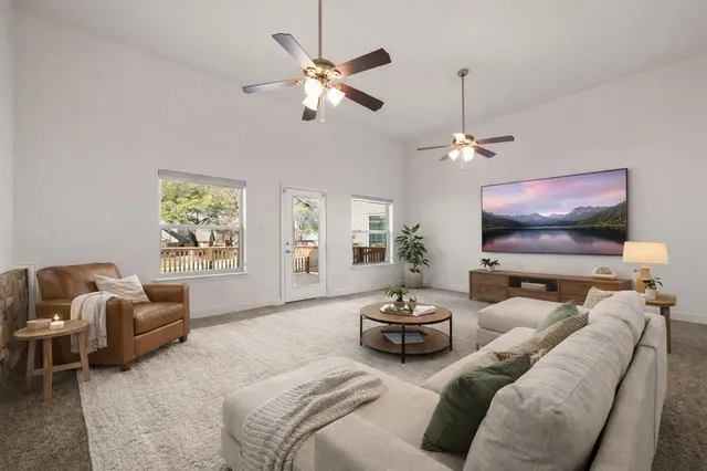 an empty room with chandelier fan and windows