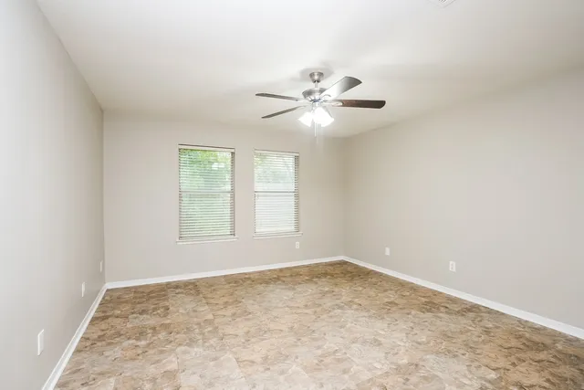 an empty room with a window and a fan
