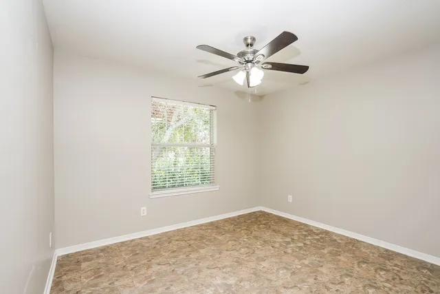 an empty room with a window and a fan