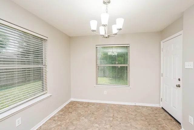 a view of a livingroom with a chandelier curtains and large windows