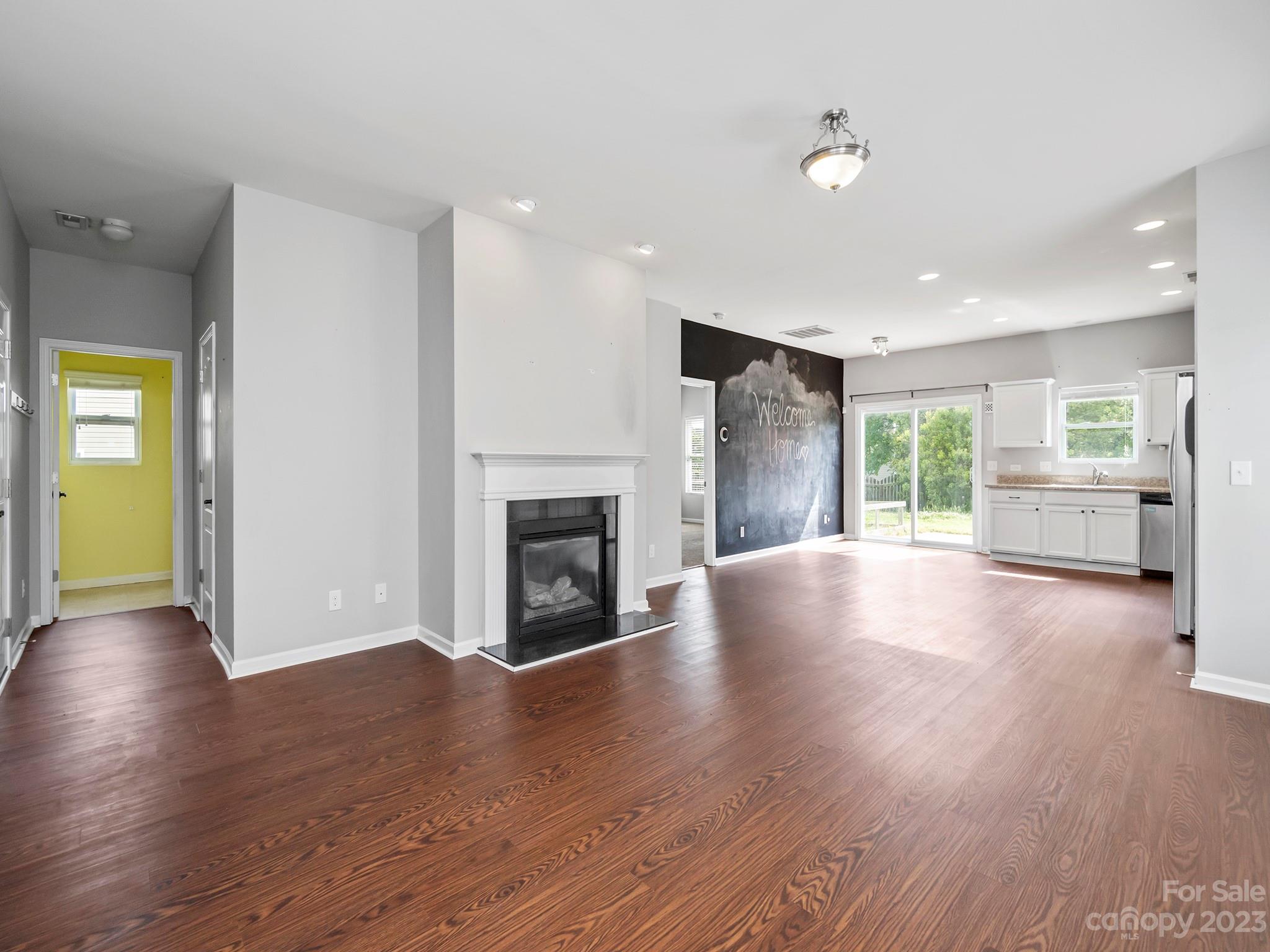 13723 Porter Creek Road Charlotte, NC 28262 - Photo 13 of 40 an empty room with wooden floor a fireplace and windows