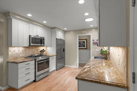 a kitchen with stainless steel appliances granite countertop a stove a sink and a refrigerator