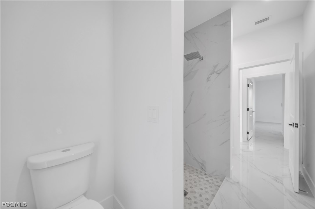 5003 2nd Street West Lehigh Acres, FL 33971 - Photo 11 of 21 a bathroom with a granite countertop toilet and shower