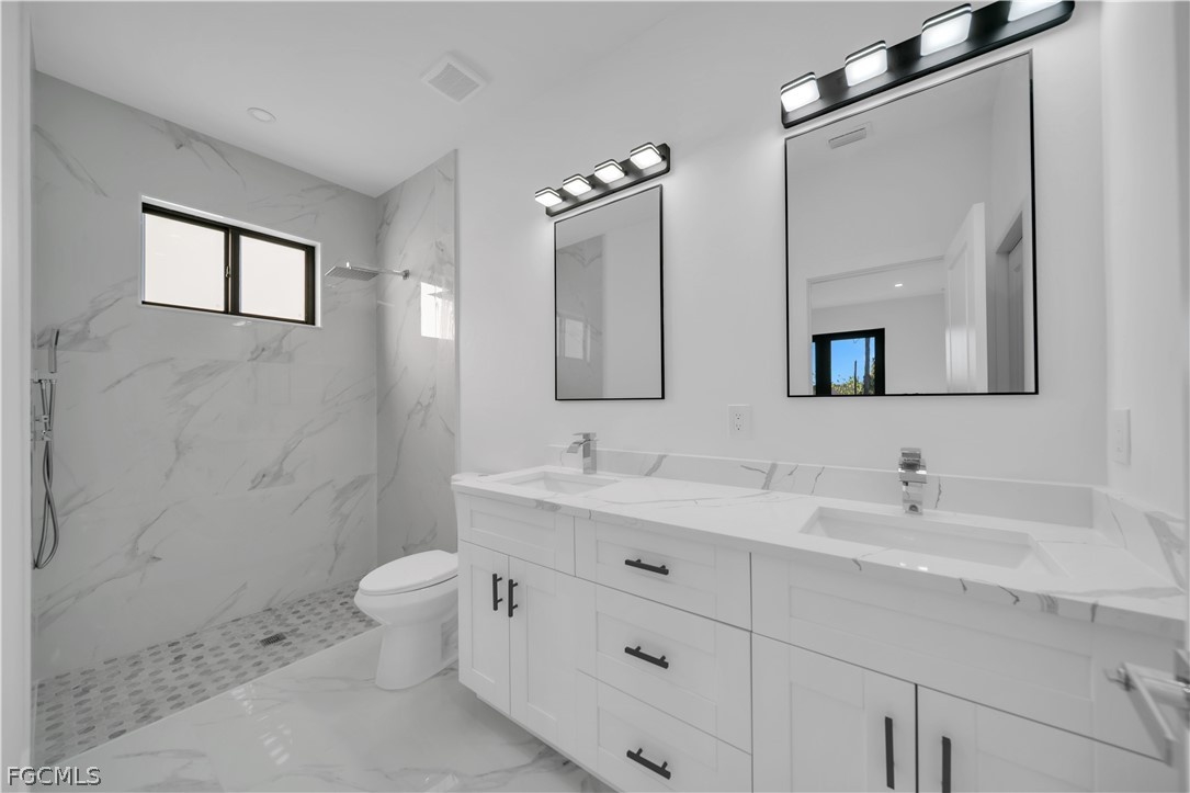 5003 2nd Street West Lehigh Acres, FL 33971 - Photo 20 of 21 a bathroom with a toilet a sink a mirror and a bathtub