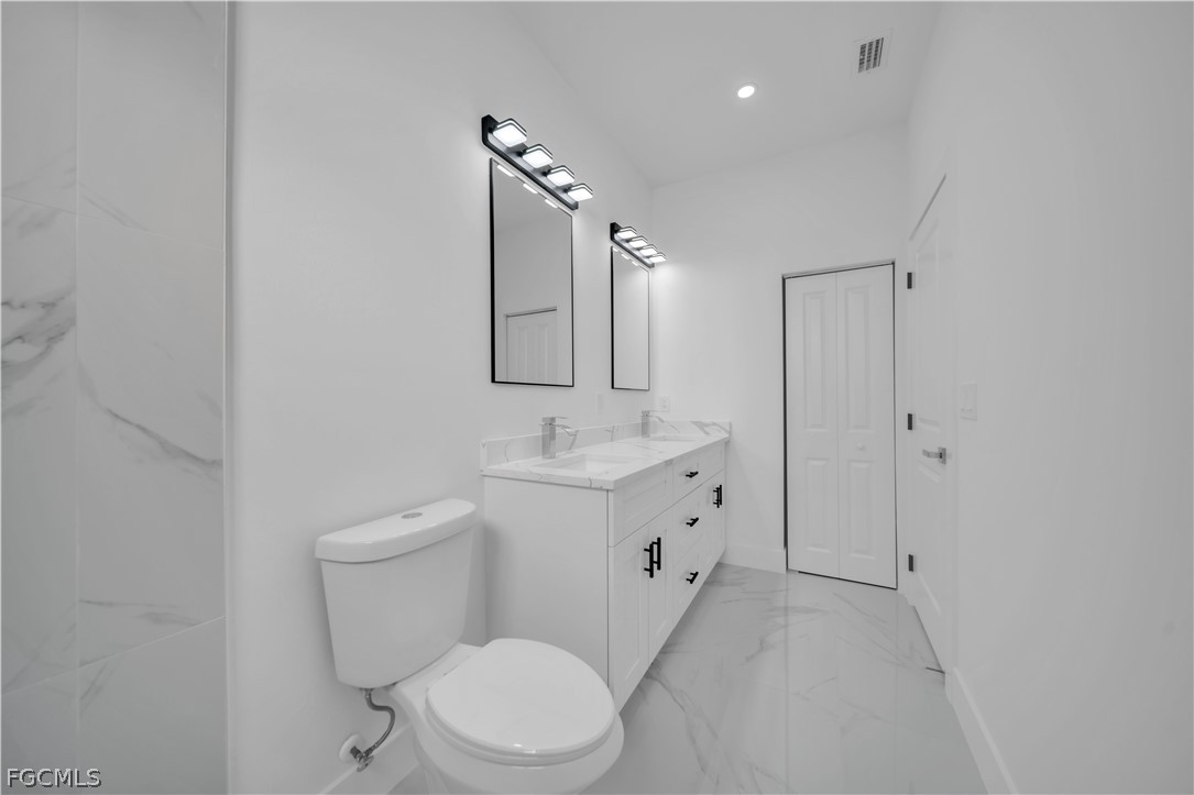 5003 2nd Street West Lehigh Acres, FL 33971 - Photo 21 of 21 a bathroom with a sink a toilet a mirror and shower