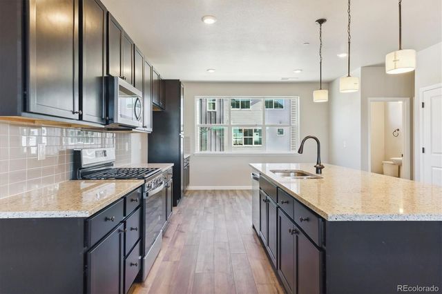 a kitchen with stainless steel appliances kitchen island a sink stove and wooden floor