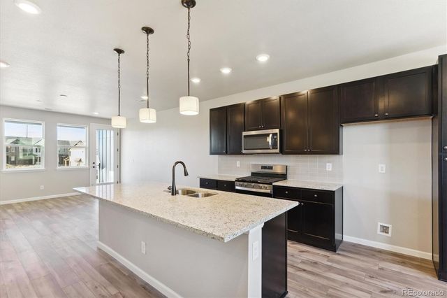 a kitchen with stainless steel appliances granite countertop a sink a stove and a wooden floors