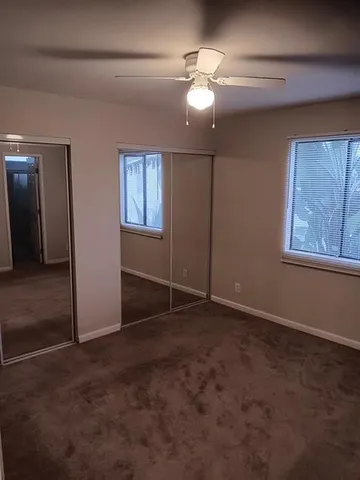 an empty room with closet and a chandelier fan