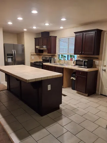 a kitchen with stainless steel appliances a stove a sink a microwave a refrigerator and cabinets