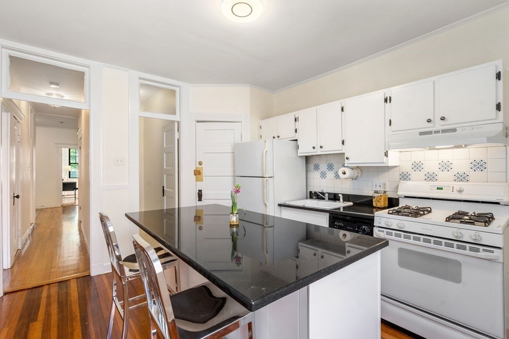 384 Riverway, Unit 5 Boston, MA 02115 - Photo 11 of 20 a kitchen with kitchen island white cabinets a sink stove and refrigerator