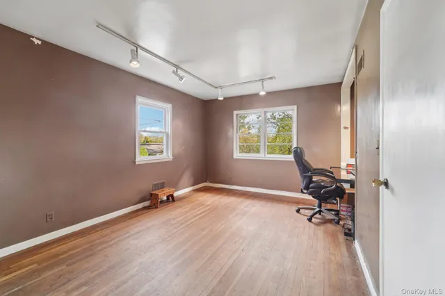a view of an empty room with a window and wooden floor