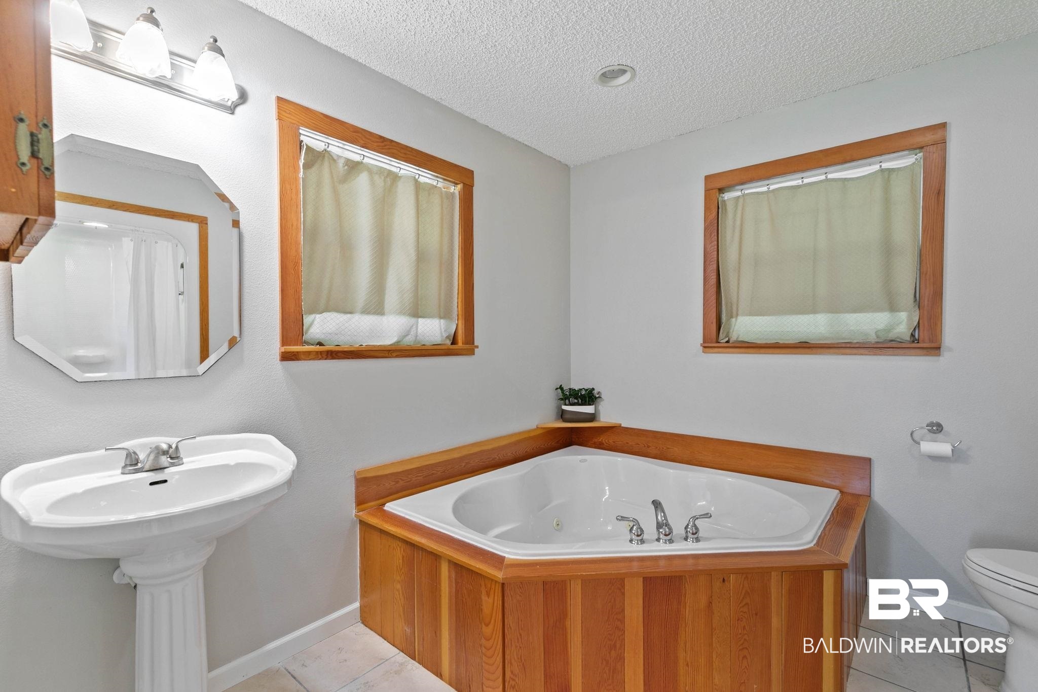20219 Greek Cemetery Road Robertsdale, AL 36567 - Photo 25 of 41 Bathroom featuring a corner built-in tub with wood-finish paneling, a pedestal sink, and an octagonal mirror