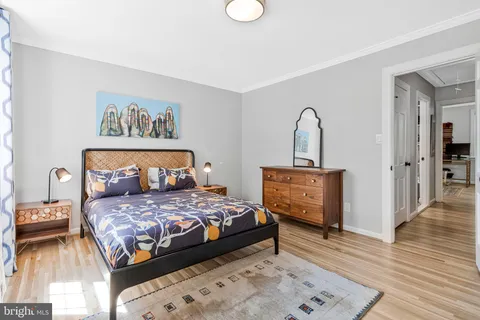 a bedroom with a bed and a dresser with wooden floor