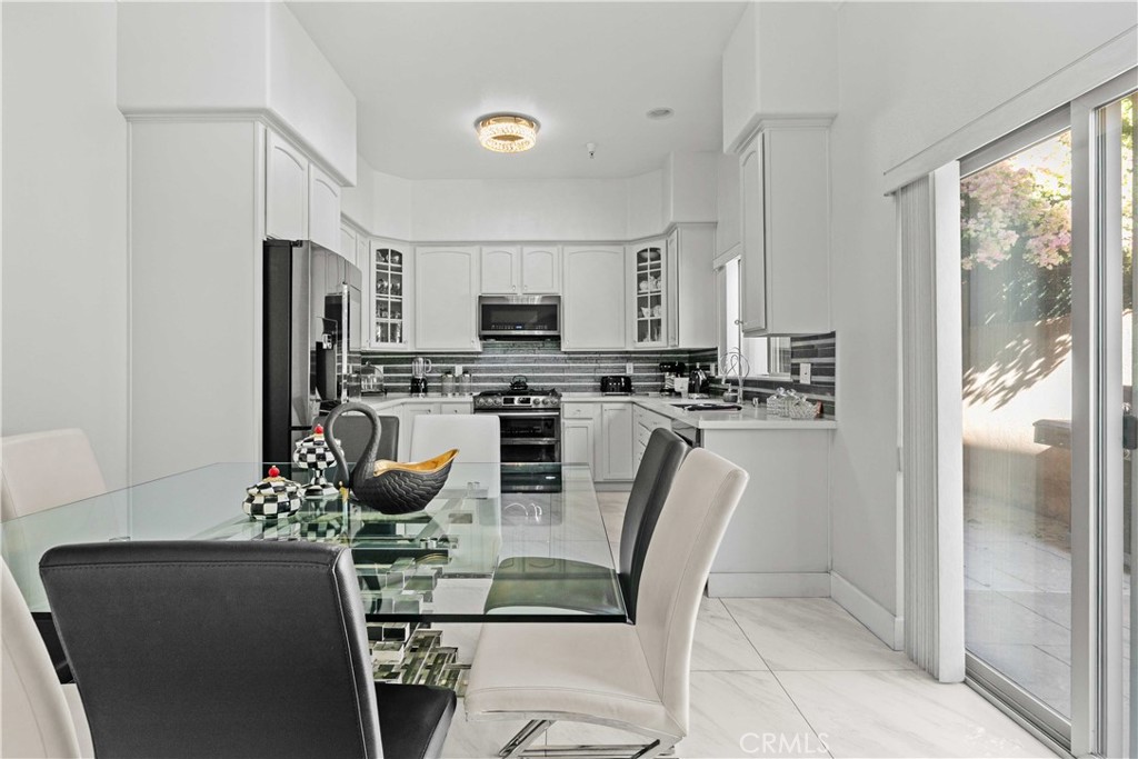 6920 Valmont Street, Unit 5 Tujunga, CA 91042 - Photo 27 of 69 a kitchen with stainless steel appliances granite countertop a refrigerator a stove a microwave oven with a dining table and chairs