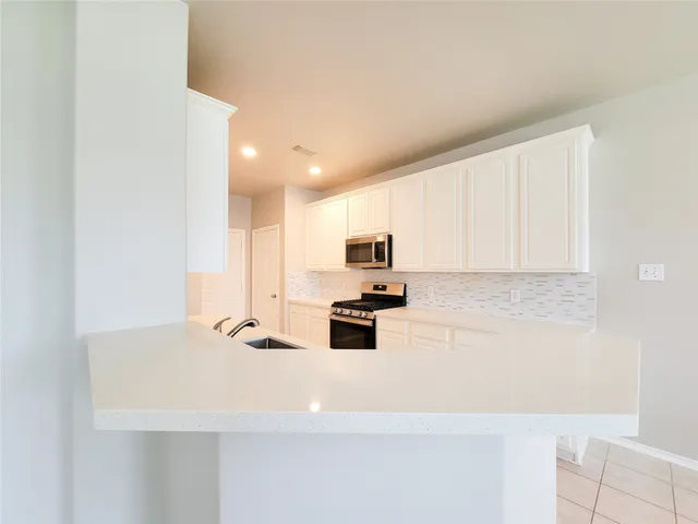 a kitchen with kitchen island a sink a stove and white cabinets