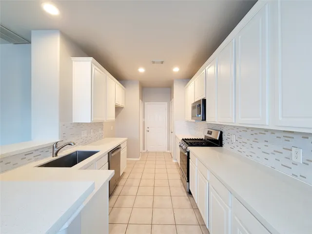 a kitchen with stainless steel appliances a sink stove top oven and cabinets