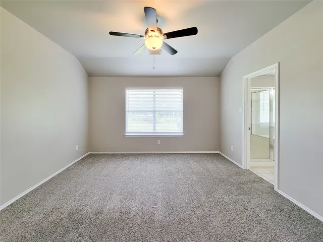 a view of an empty room with a ceiling fan and window