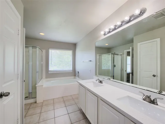 a spacious bathroom with a double vanity sink a mirror and a bathtub
