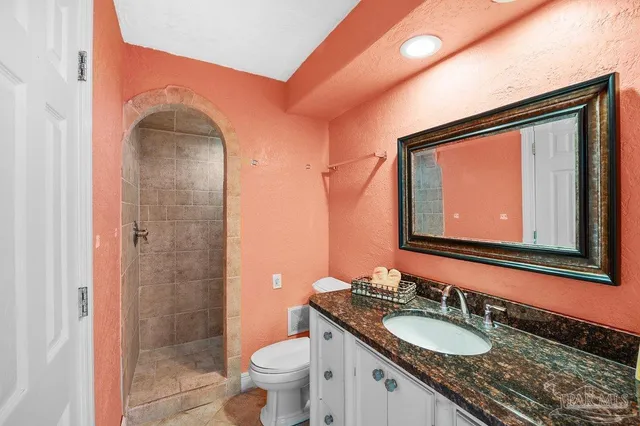 a bathroom with a granite countertop sink toilet a mirror and shower