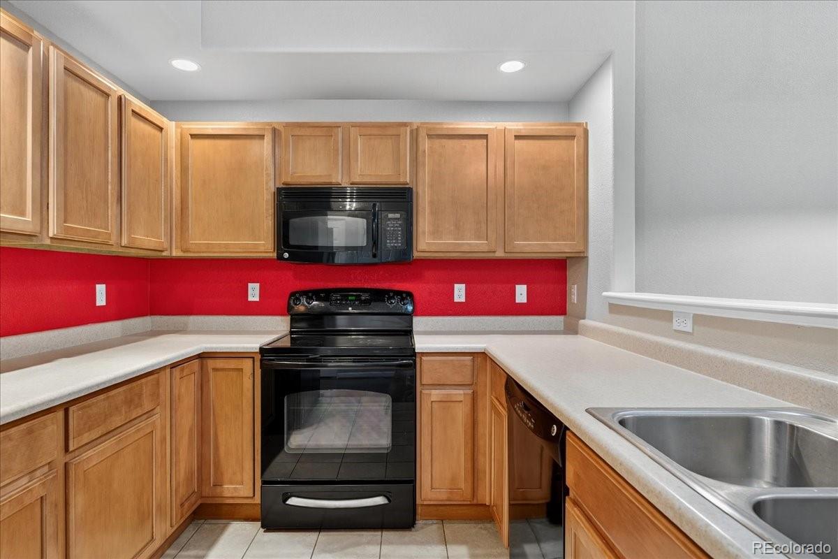 5800 Tower Road, Unit 2411 Denver, CO 80249 - Photo 8 of 28 a kitchen with stainless steel appliances granite countertop a stove a sink and a microwave
