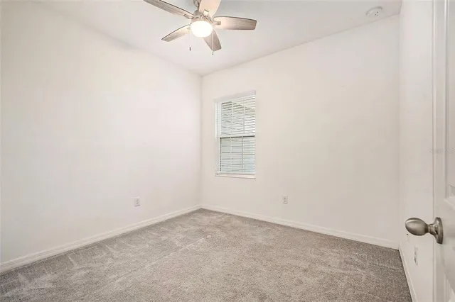 an empty room with a window and a fan