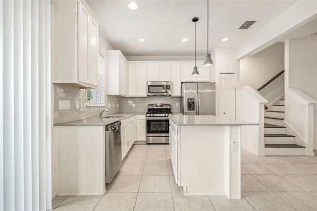 a kitchen with stainless steel appliances kitchen island granite countertop a stove and a sink