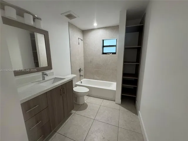 a bathroom with a bathtub sink vanity mirror and toilet