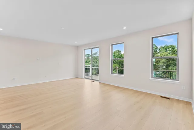 a view of an empty room with a window and a kitchen
