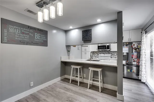 a kitchen with stainless steel appliances kitchen island granite countertop a sink cabinets and wooden floor