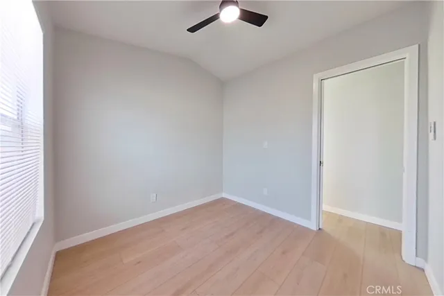 an empty room with a ceiling fan and wooden floor