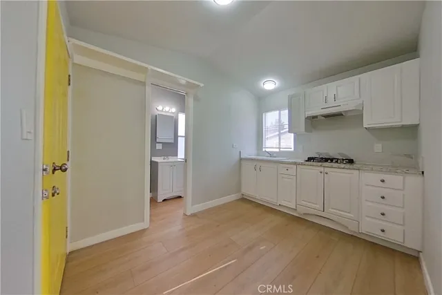 a kitchen with granite countertop white cabinets and wooden floor