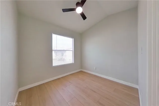 an empty room with wooden floor ceiling fan and windows