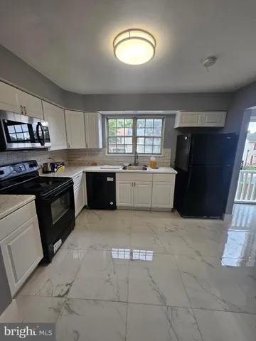 a large kitchen with a stove top oven a sink a counter space and cabinets