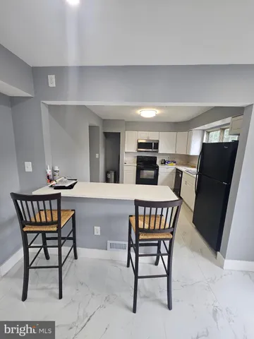 a room with chairs a table and a a refrigerator