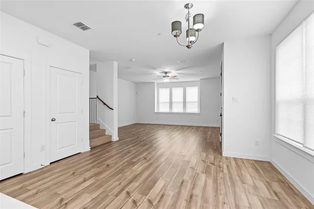 an empty room with wooden floor cabinet and windows