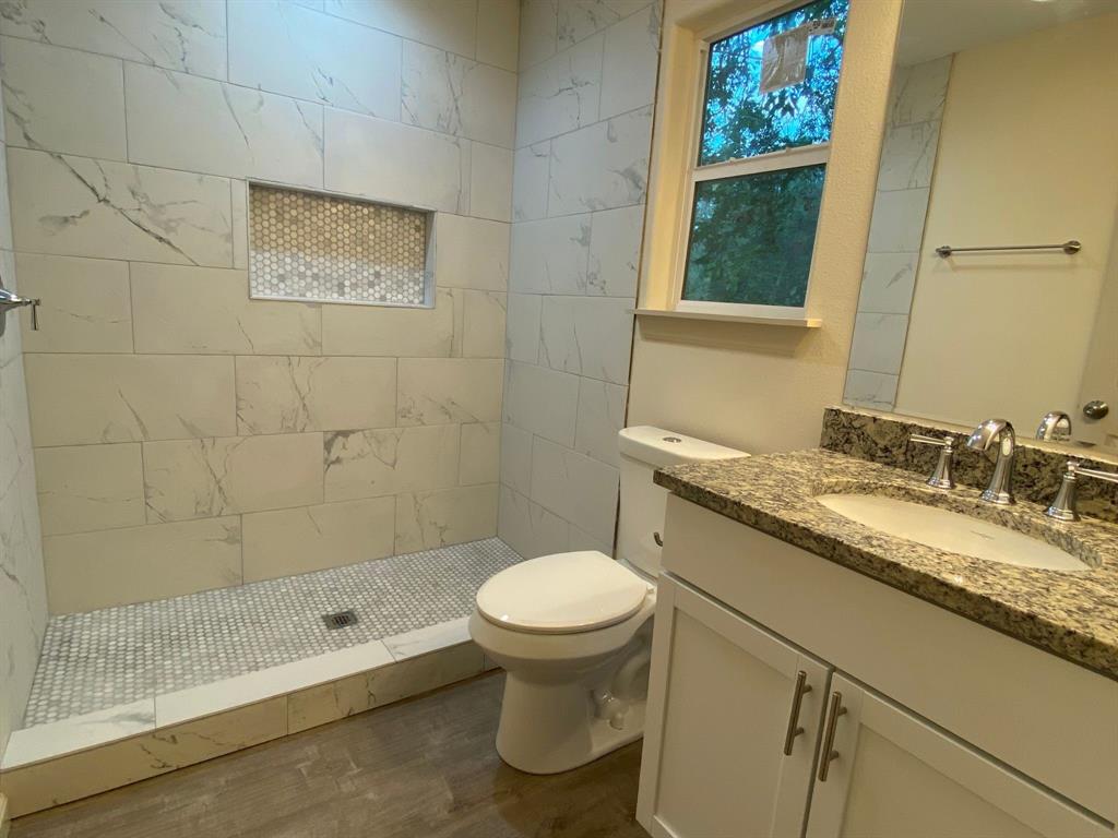 a bathroom with a granite countertop sink a toilet and a shower