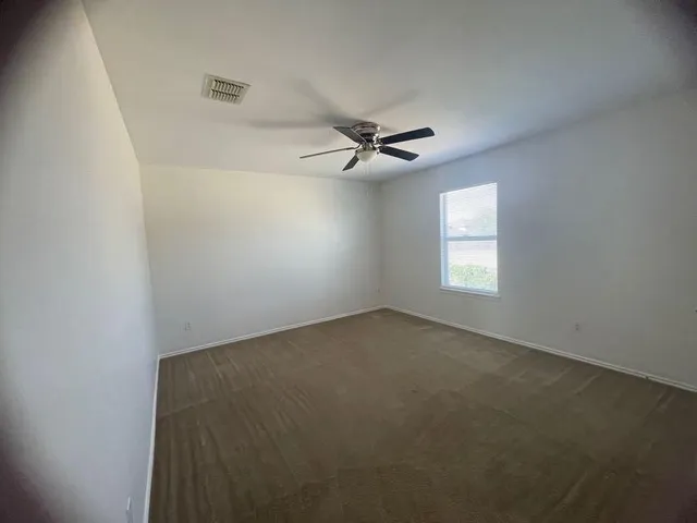 an empty room with windows and fan