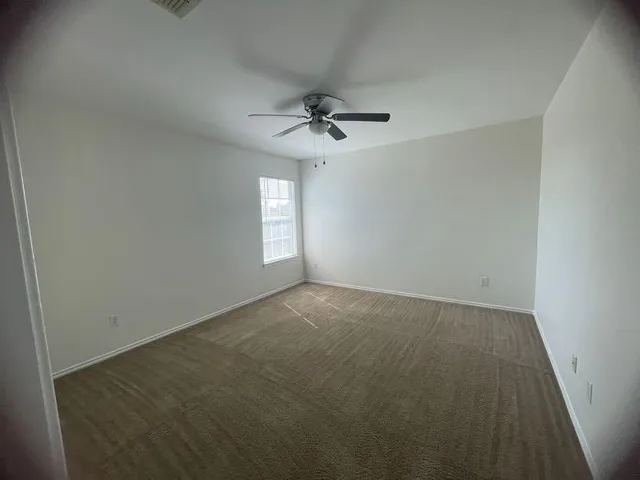 an empty room with a ceiling fan and window