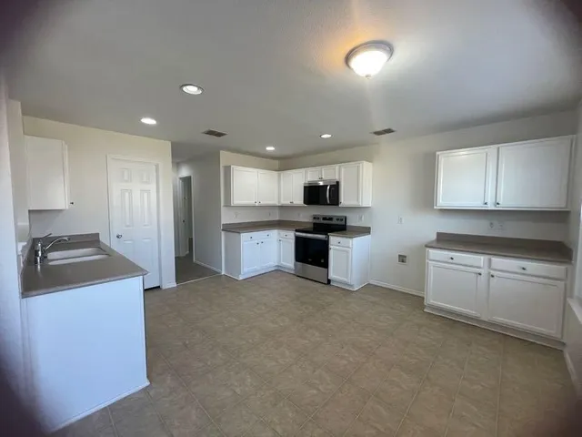 a kitchen with stainless steel appliances granite countertop a stove a sink a refrigerator and white cabinets