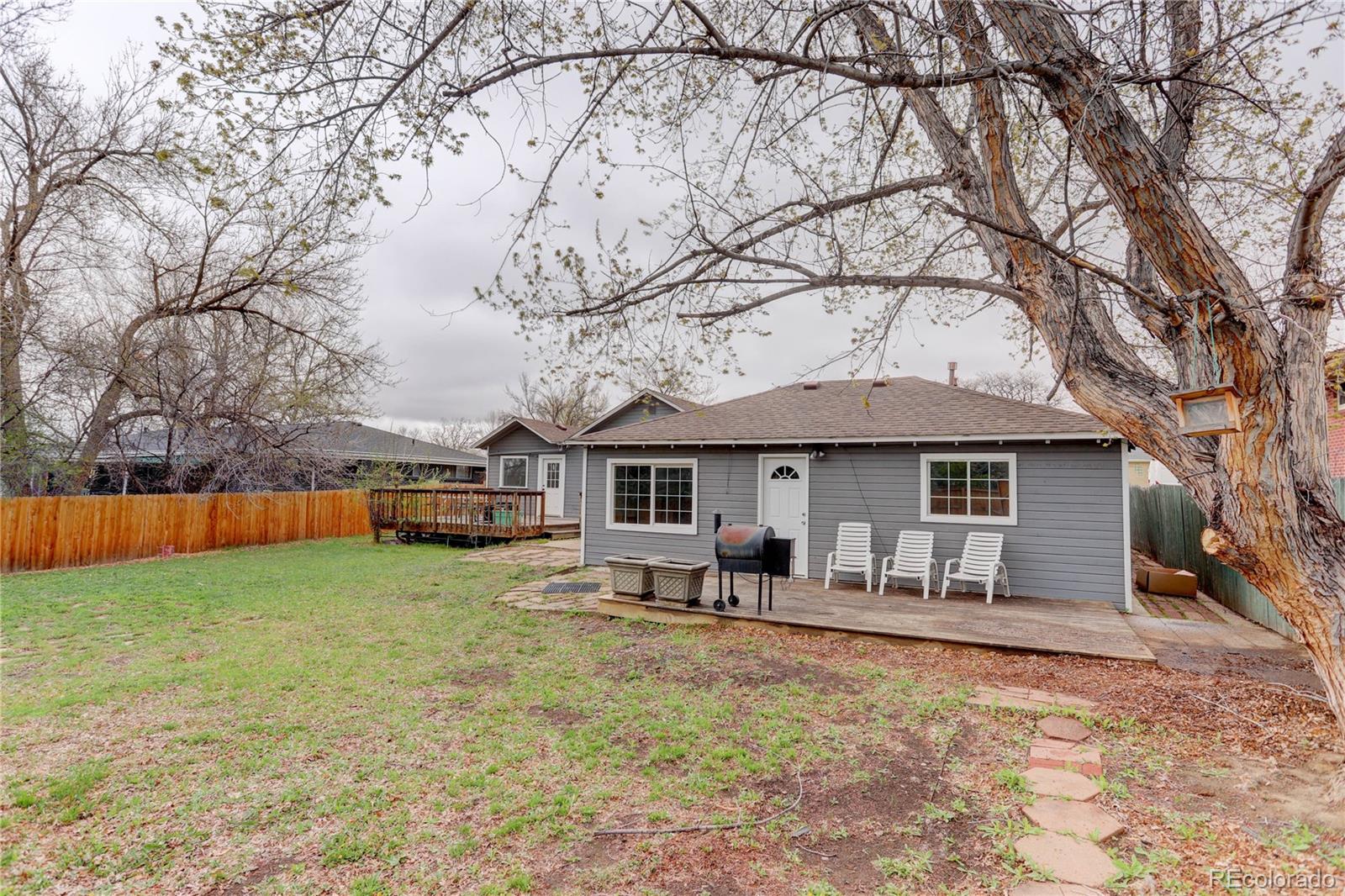4315 Balsam Street Wheat Ridge, CO 80033 - Photo 30 of 34 a backyard of a house with table and chairs under an umbrella